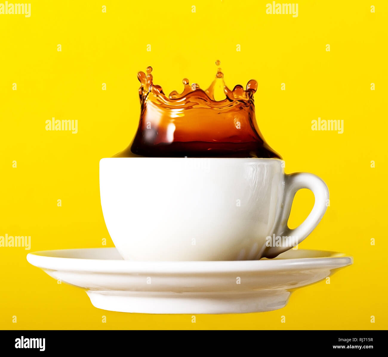 Lecker frischen schwarzen Kaffee in Schale splash Krone auf gelb leuchtenden Hintergrund. Art Design Kreativität Idee Stockfoto