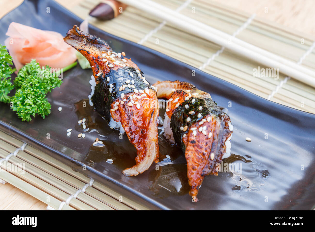 Japanisches Essen Unagi Sushi ist Aal Fisch vom Grill und Reis mit süßer  Soße in schwarze Platte auf Holztisch befeuchten Stockfotografie - Alamy