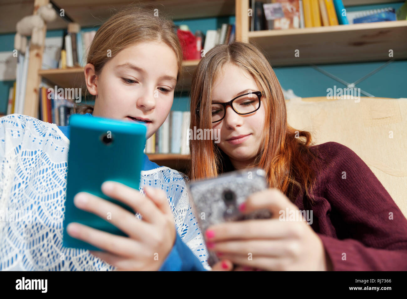 2 Mädchen, 10 und 12 Jahre alt, spielen, stand Smartphones Stockfoto