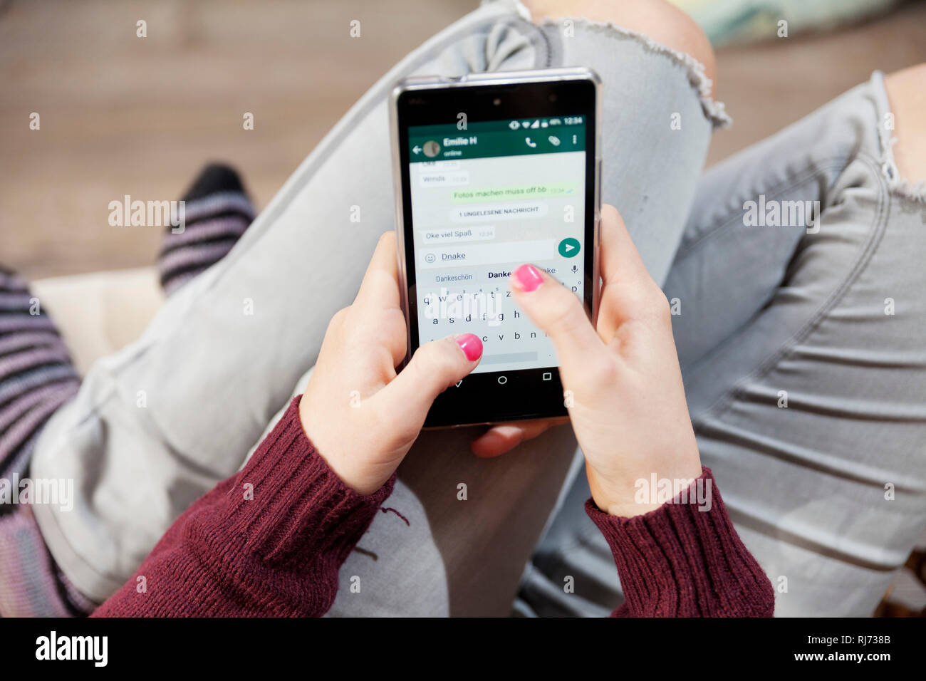 Mädchen, 12 Jahre alt, tippt eine Nachricht in ihr Smartphone Stockfoto