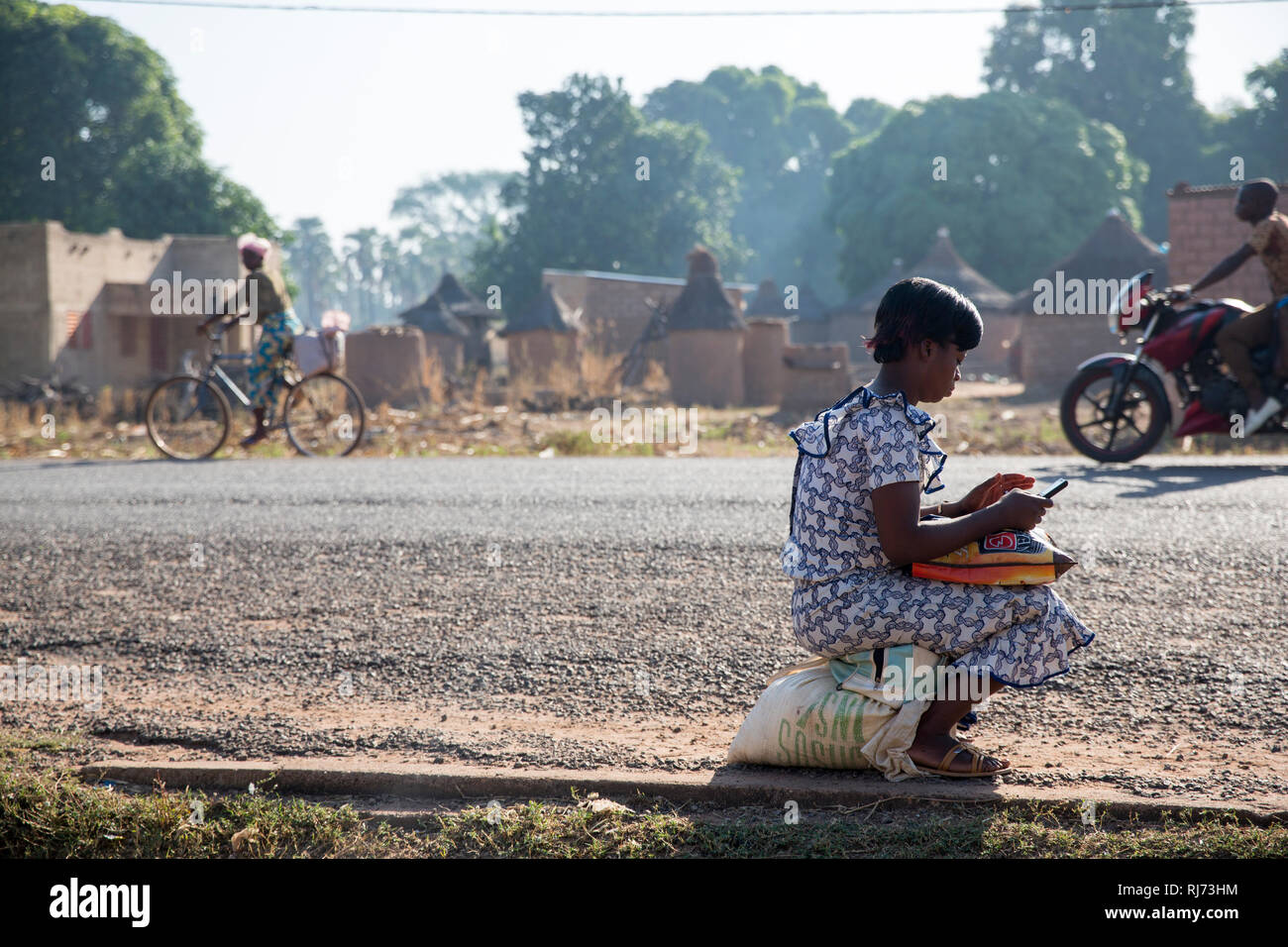 Diarabakoko-Dorf, Banfora, Cascades Region, Burkina Faso, 5. Dezember 2016; EINE Frau kontrolliert ihr Handy am Straßenrand. Stockfoto