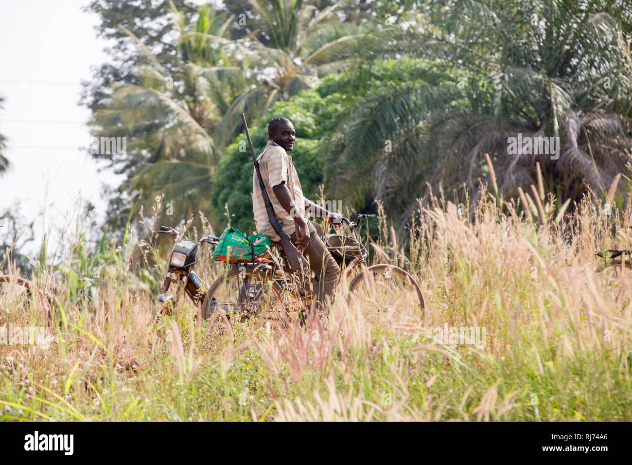 Karfiguela Dorf, Banfora, Cascades Region, Burkina Faso, 6. Dezember 2016; ein Jäger auf dem Fahrrad auf dem Weg nach Buschfleisch zu suchen. Stockfoto