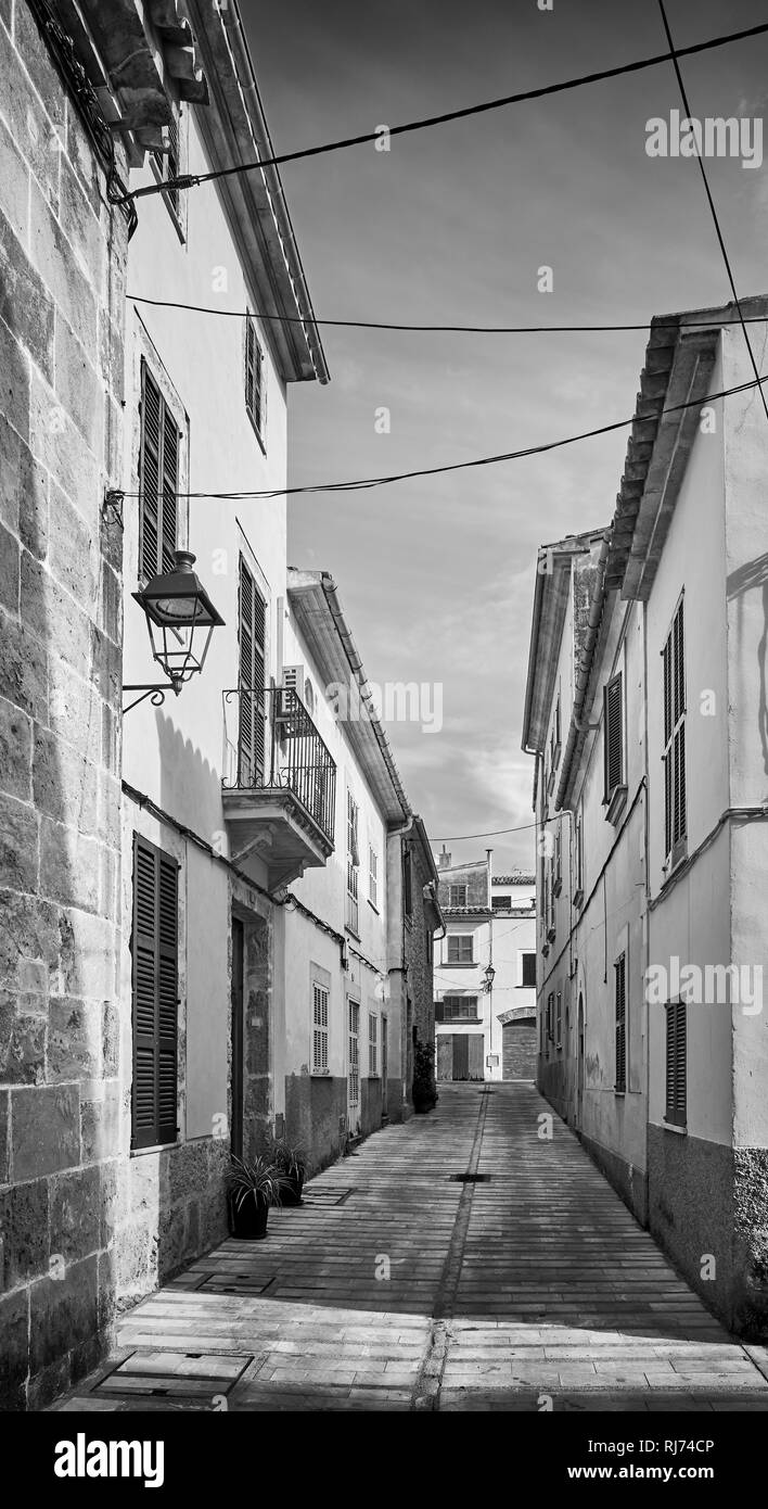 Schwarz-weiß Bild von einer engen Straße in der Altstadt von Alcudia, Mallorca, Spanien. Stockfoto