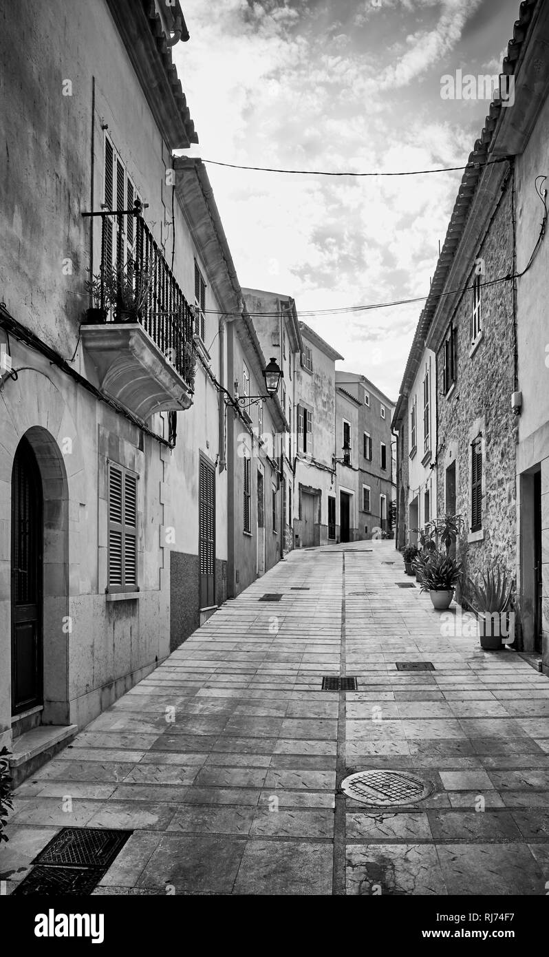 Schwarz-weiß Bild von einer engen steilen Straße in der Altstadt von Alcudia, Mallorca, Spanien. Stockfoto