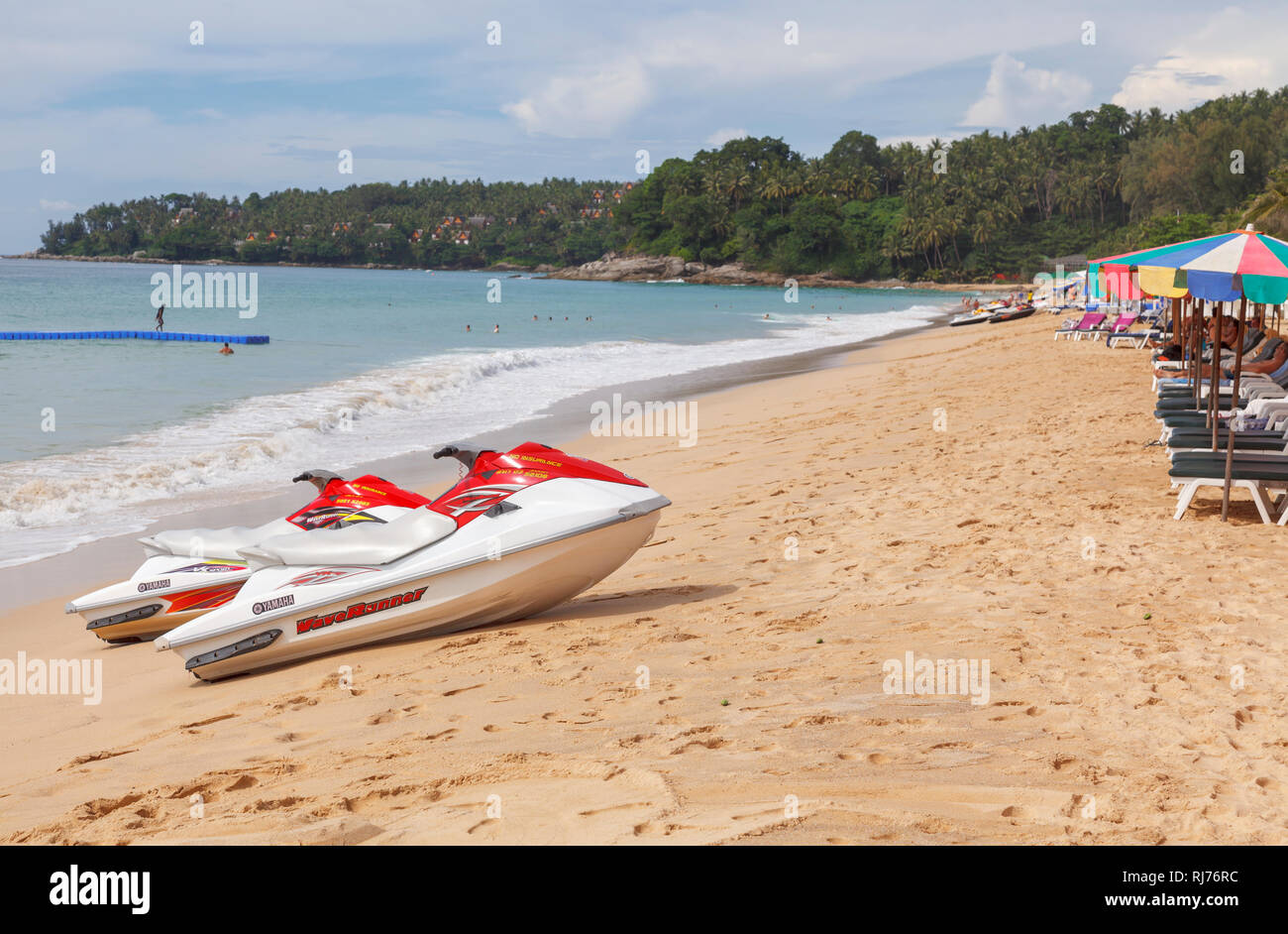 Rot und Weiß Yamaha Waverunner Jetskis am Strand vor bunten Sonnenschirme und Liegestühle in Surin Beach, West Coast Pkuket, Thailand Stockfoto