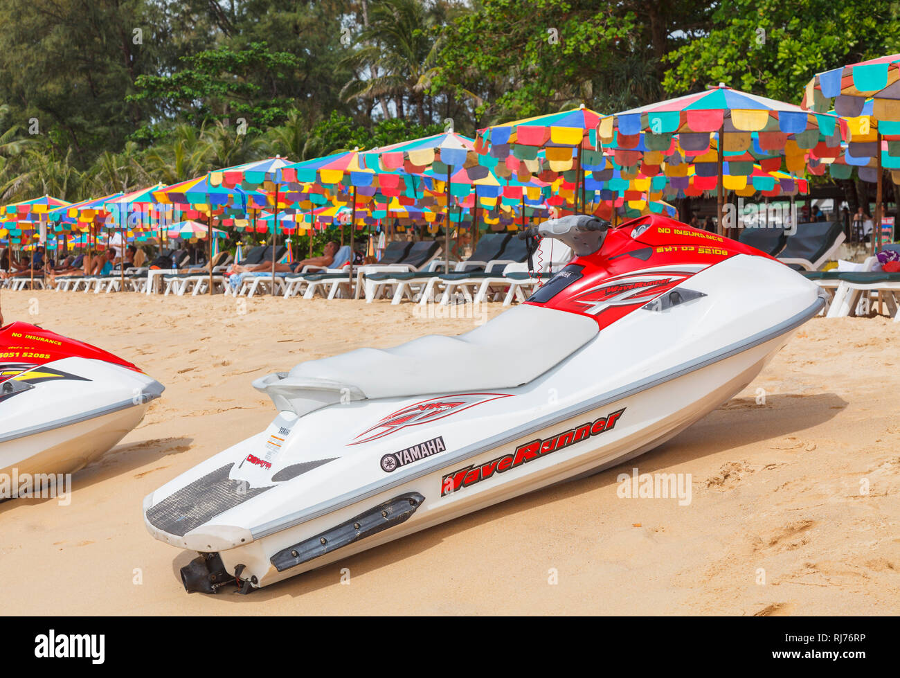 Rot und Weiß Yamaha Waverunner Jetski am Strand vor bunten Sonnenschirme und Liegestühle in Surin Beach, West Coast Pkuket, Thailand Stockfoto