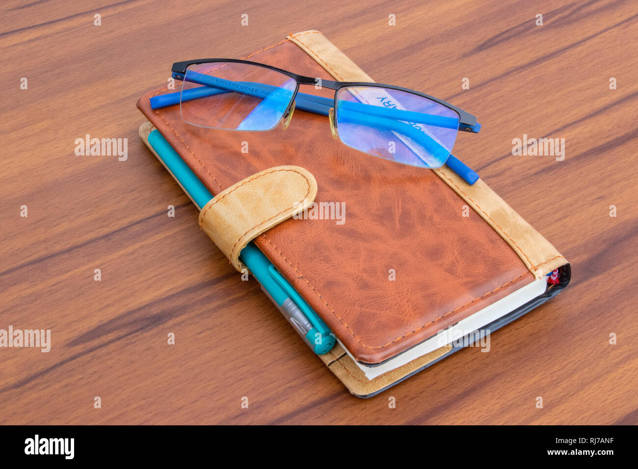 Braunes Bürotagebuch mit Kugelschreiber und Glas auf hellem Holzhintergrund Stockfoto