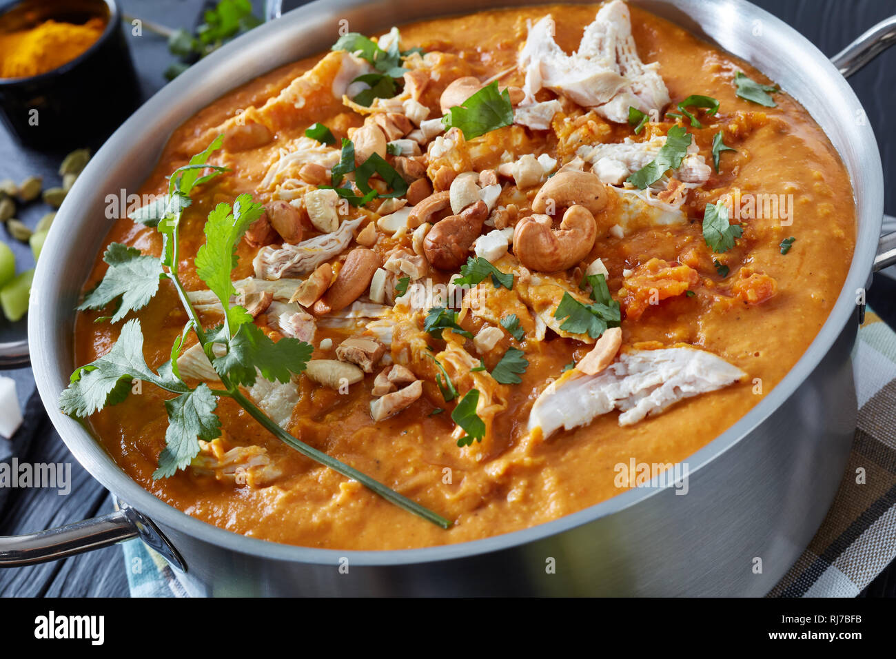 In der Nähe von herzhaft würzige Mulligatawny Suppe in einer Kasserolle aus Metall auf einem schwarzen Holztisch mit einer Suppenkelle und Zutaten, Indische und englische Küche Stockfoto