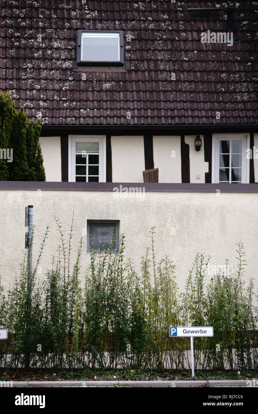 Ein Parkplatzschild für Gewerbe vor einem Fachwerkhaus mit Mauer. Stockfoto