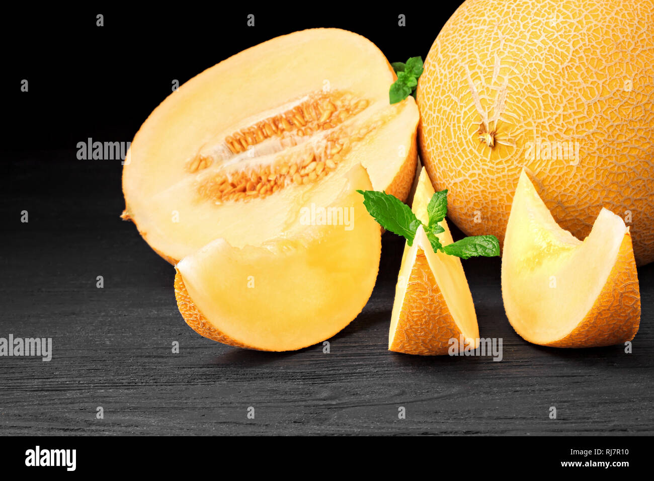 Frischen süßen Orangen Melone auf einem alten schwarzen Holztisch auf schwarzen Hintergrund (selektive Fokus). Stockfoto