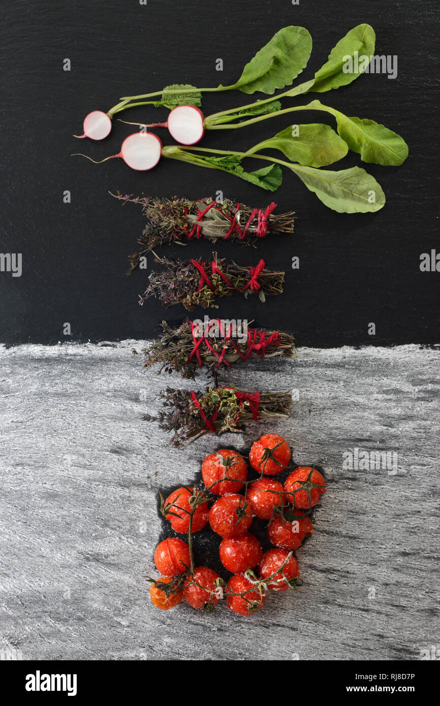 Gewürzsträußchen, gebackene Tomaten und frische Radieschen Stockfoto