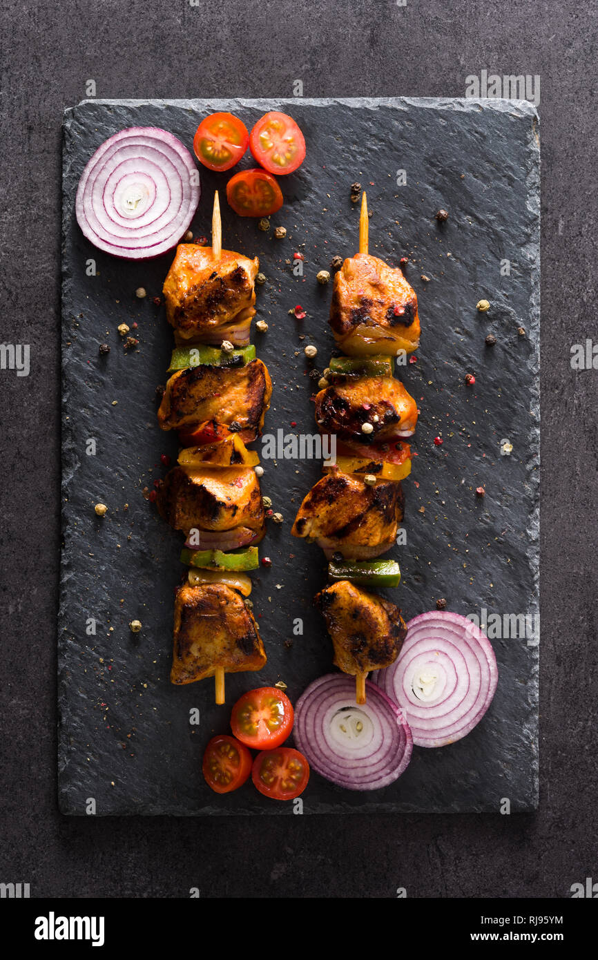 Hühnchen Shish Kebab mit Gemüse auf schwarzem Stein. Ansicht von oben Stockfoto