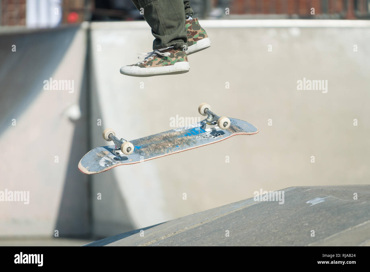 Die Schuhe und Beine eines Skater, wie sie durch die Luft fliegen und das Skateboard auf den Boden fällt an der Hove Lagune Skatepark, Hove, Brighton, UK. Stockfoto