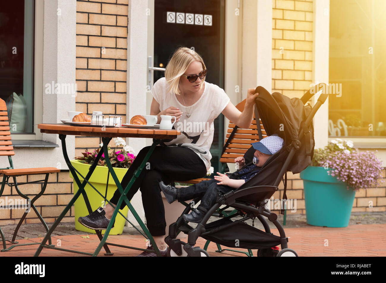 Junge Mutter mit ihrem einjährigen Kind in einer Street Cafe Stockfoto