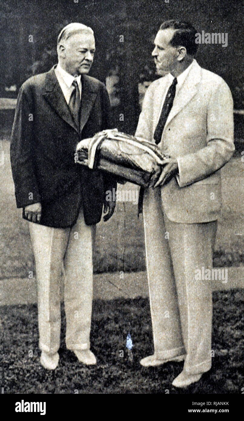 Foto von Präsident Herbert Hoover brechen Brot mit seinen olympischen Gast als Zeichen der Gastfreundschaft während der Olympischen Spiele 1932 in Los Angeles statt. 20. Präsident Herbert Hoover (1874-1964) ein US-amerikanischer Politiker und der 31. Präsident der Vereinigten Staaten von Amerika. Vom 20. Jahrhundert Stockfoto