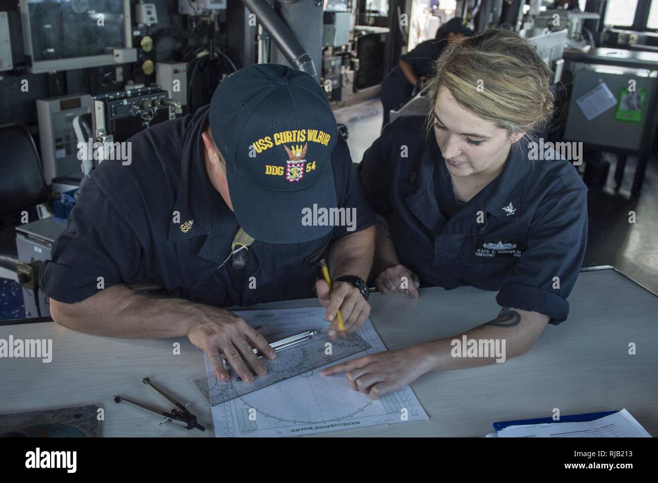 Philippinischen MEER (Nov. 2, 2016) Petty Officer 3rd Class Kate Coughlin, rechts, lehrt Senior Chief Petty Officer Jason Scott, Links, wie man richtig mit einem manövrieren Board stehend Quartiermeister der Uhr auf der Brücke der Arleigh-Burke-Klasse geführte Anti-raketen-Zerstörer USS Curtis Wilbur (DDG54). Curtis Wilbur ist auf Patrouille im philippinischen Meer Unterstützung der Sicherheit und Stabilität in der Indo-Asia-Pazifik-Region. Stockfoto