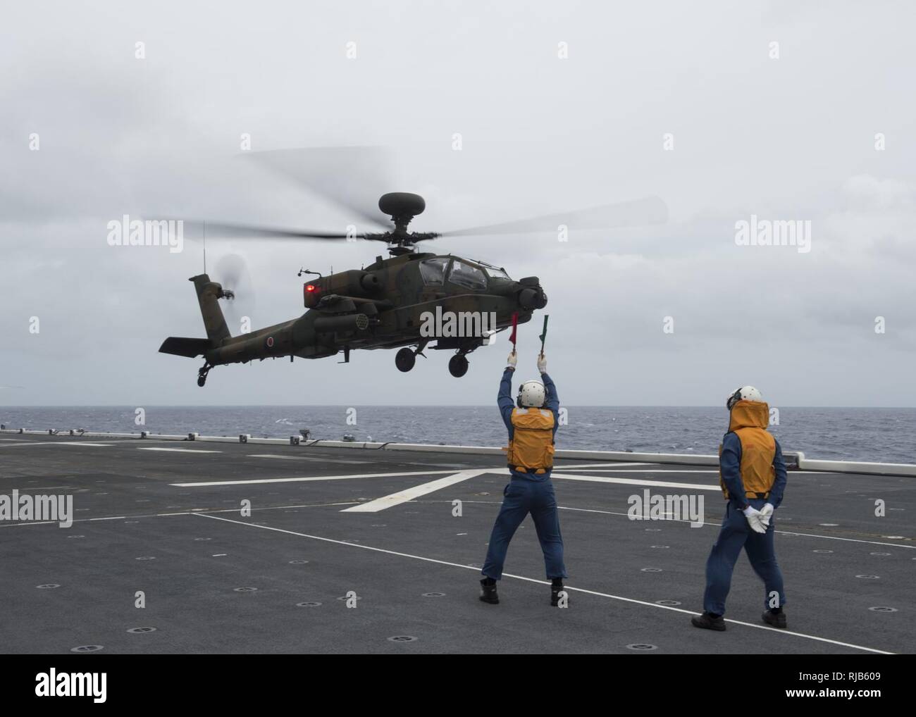Pazifik (Nov. 4, 2016) - Flight Deck Besatzungsmitglieder Signale einer japanischen Boden Self Defense Force AH-64 Apache Helikopter für Nehmen Sie an Bord des Japanischen Schiff (JS) Hyuga (DDH181) während der Übung scharfes Schwert 2017. Scharfes Schwert 17 ist ein gemeinsames und bilateralen Bereich Training (Ftx) zwischen US-amerikanischen und japanischen Truppen bedeutete die Bereitschaft und die Interoperabilität im Rahmen des U.S.-Japan Alliance zu erhöhen. Stockfoto