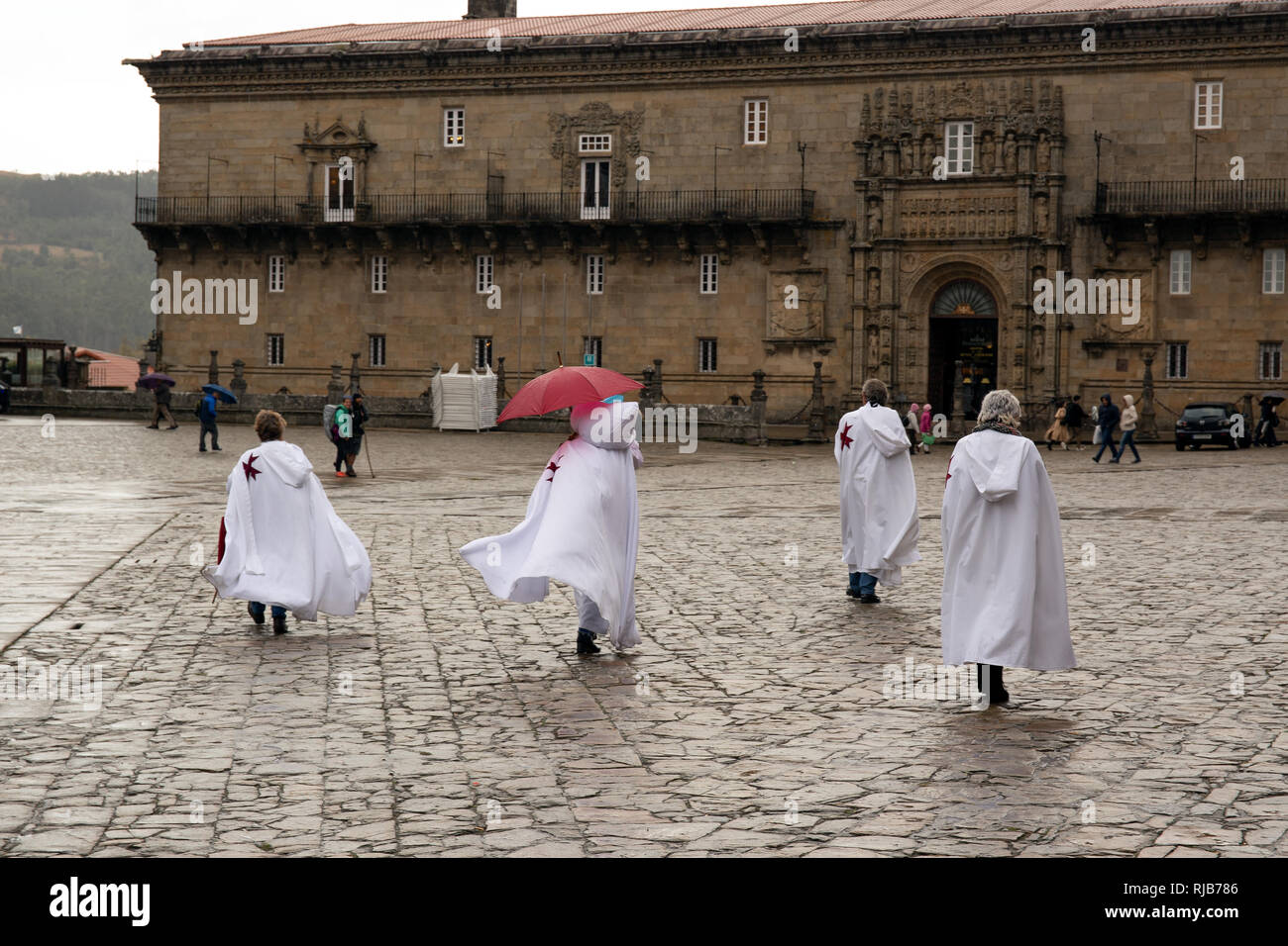Die Menschen tragen weisse Gewohnheit auf Obradoiro Square, Santiago de Compostela, Spanien. Hostal de los Reyes Catolicos im Hintergrund Stockfoto
