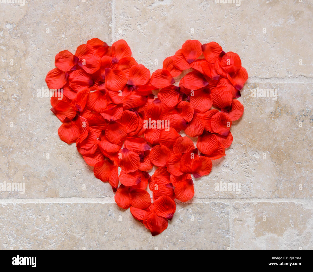 Ein Herz aus Rosenblättern auf den Boden gelegt als ein Konzept von Liebe und Valentinstag. Stockfoto