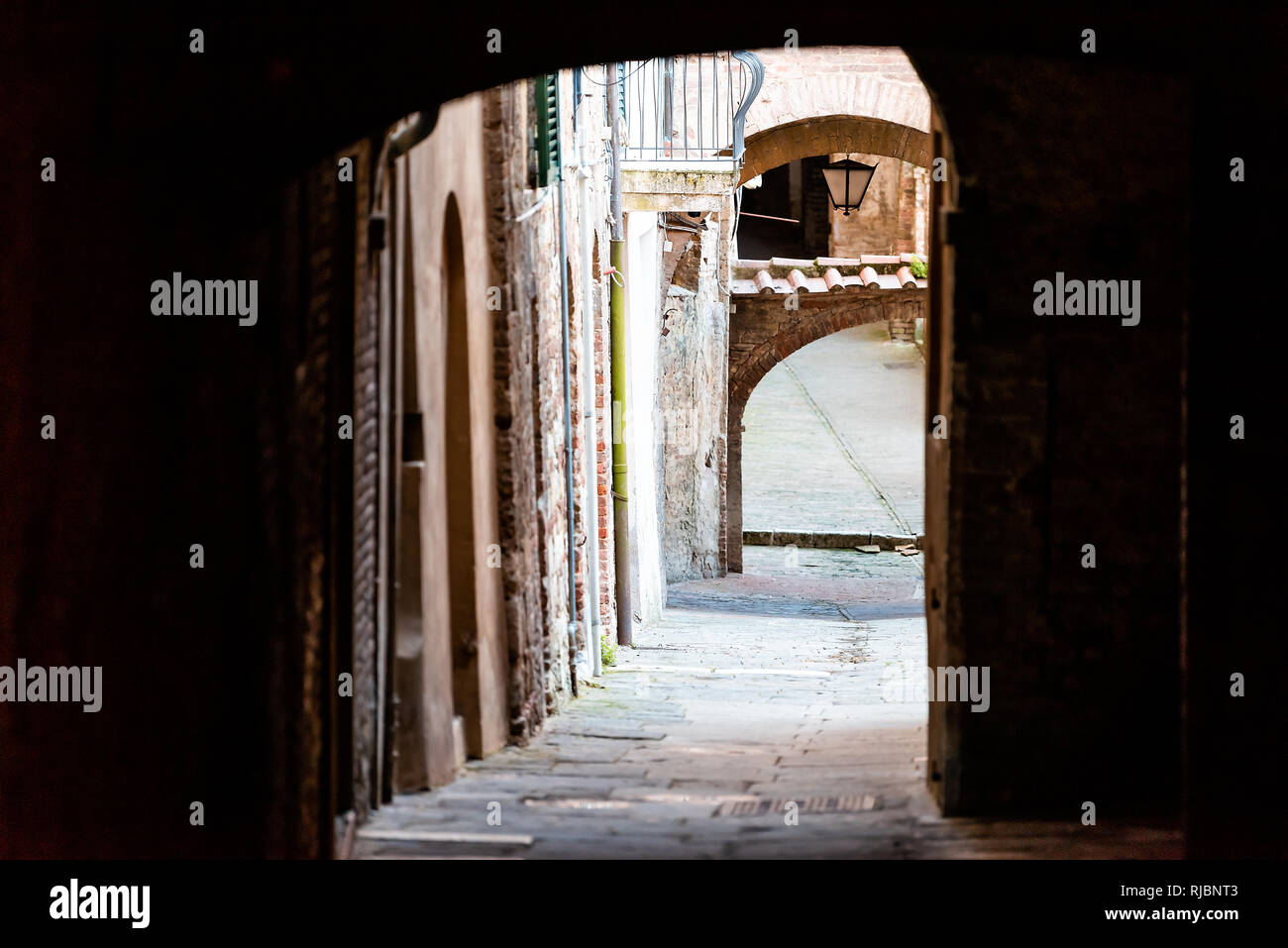 Siena, Italien dunkle schmale Gasse Straße in der historischen, mittelalterlichen Altstadt Dorf in der Toskana mit niemand und arch Tunnel passage Stockfoto