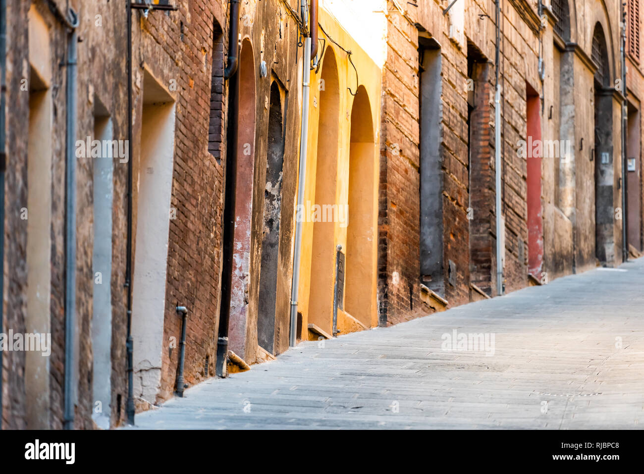 Siena, Italien engen steilen Gasse Straße in der historischen, mittelalterlichen Altstadt Dorf in der Toskana mit niemand im Sommer Tag und Gelb farbenfrohe Architektur Stockfoto