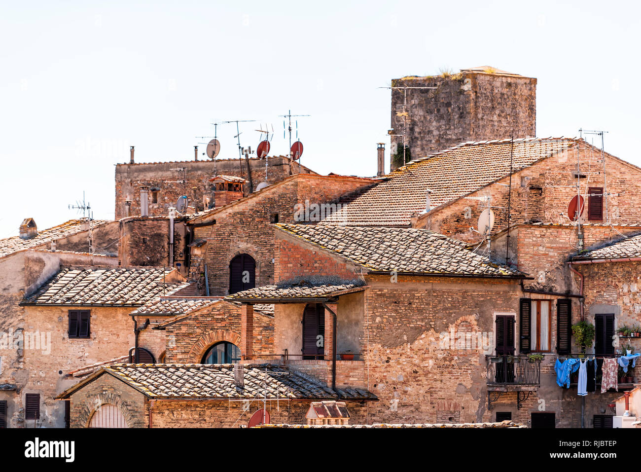 San Gimignano, Italien Dachterrasse mit historischen alten mittelalterlichen Gebäude der Stadt Dorf orange Stein im Sommer Dachziegel closeup und Satellitenschüsseln citys Stockfoto