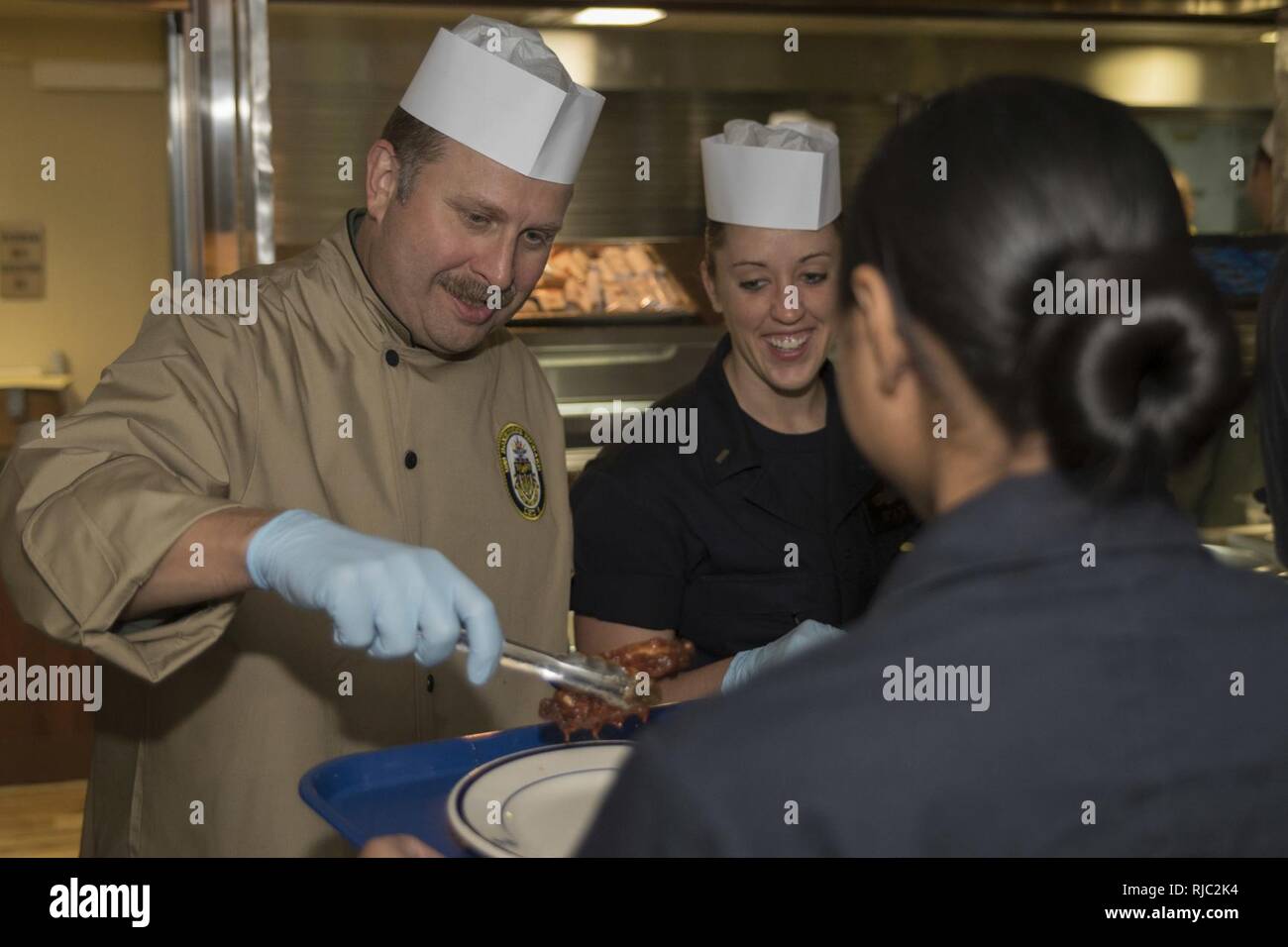 EAST CHINA SEA (Nov. 1, 2016) Kapitän Larry McCullen, Executive Officer der Amphibisches Schiff USS BONHOMME RICHARD (LHD 6), Chicken Wings, Seaman Salima Morris während einer Food Service Assistant und kochen Anerkennung Nacht in den Wardroom statt. Bonhomme Richard und amphibische Schiffe unter amphibischen Squadron 11 sind in der letzten Phase einer multi-Monat Patrouille im Indo-Asia Pazifik nach dem Aussteigen marines Der 31 Marine Expeditionary Unit. Stockfoto