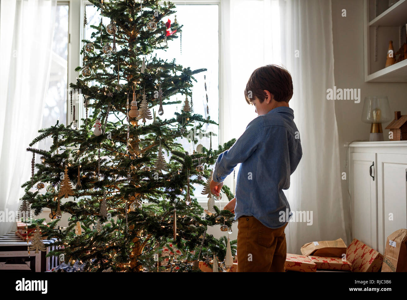 Junge, einen Weihnachtsbaum zu verzieren Stockfoto