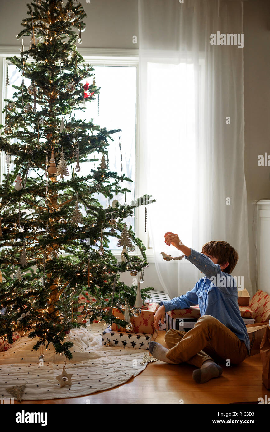 Junge hängende Dekorationen am Weihnachtsbaum Stockfoto