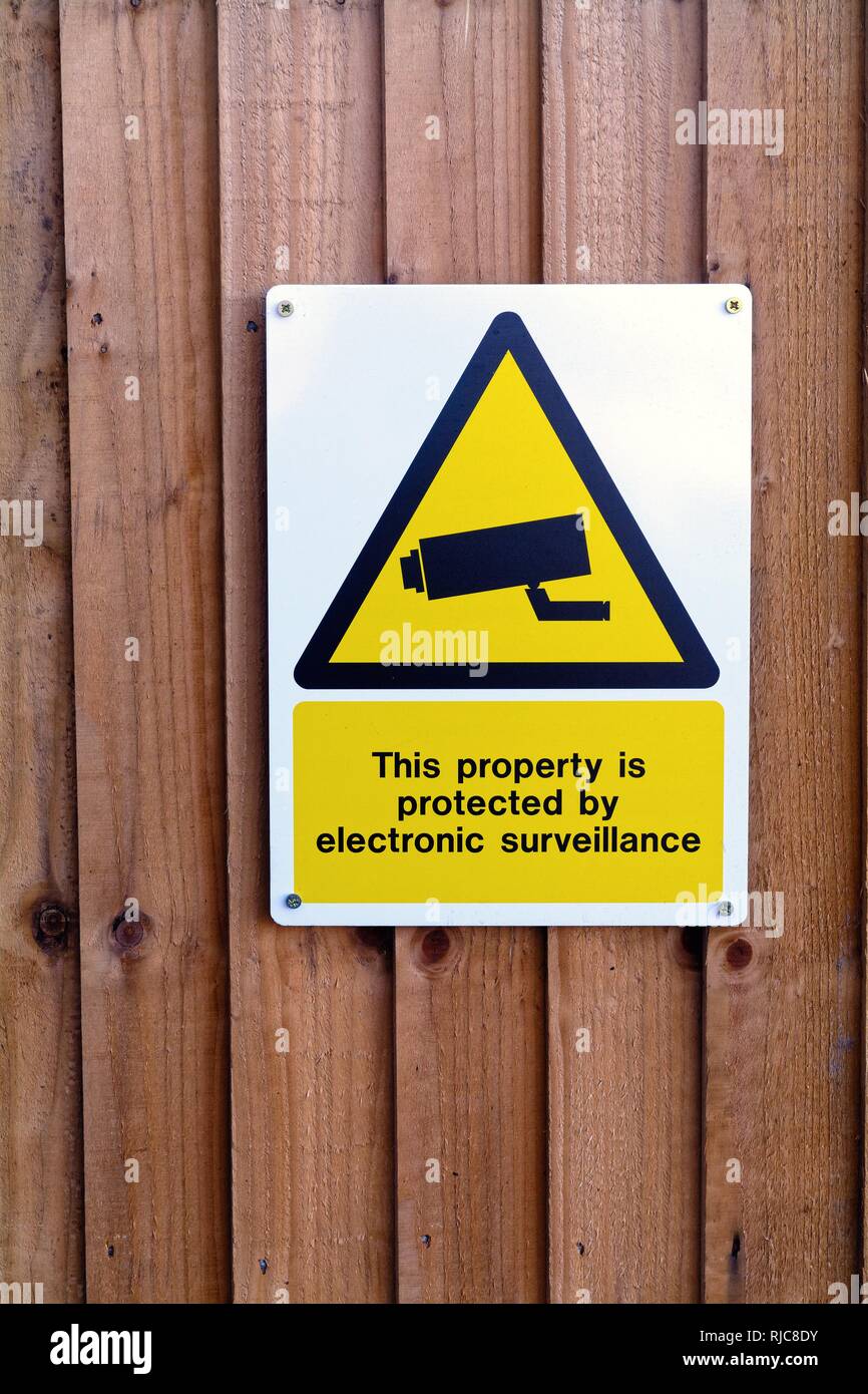 Nahaufnahme von einem Zeichen der Unterrichtung der Öffentlichkeit, dass "diese Eigenschaft durch elektronische Überwachung" zu einem Holzzaun UK befestigt ist geschützt Stockfoto