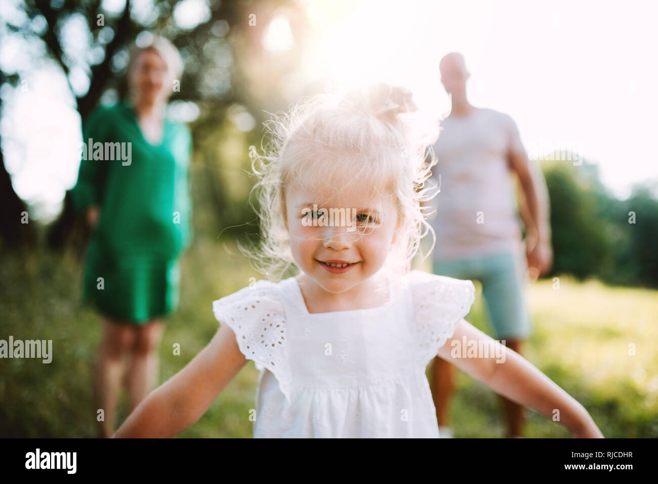 Ein kleines Mädchen mit unkenntlich Eltern im sonnigen Sommer Natur. Stockfoto