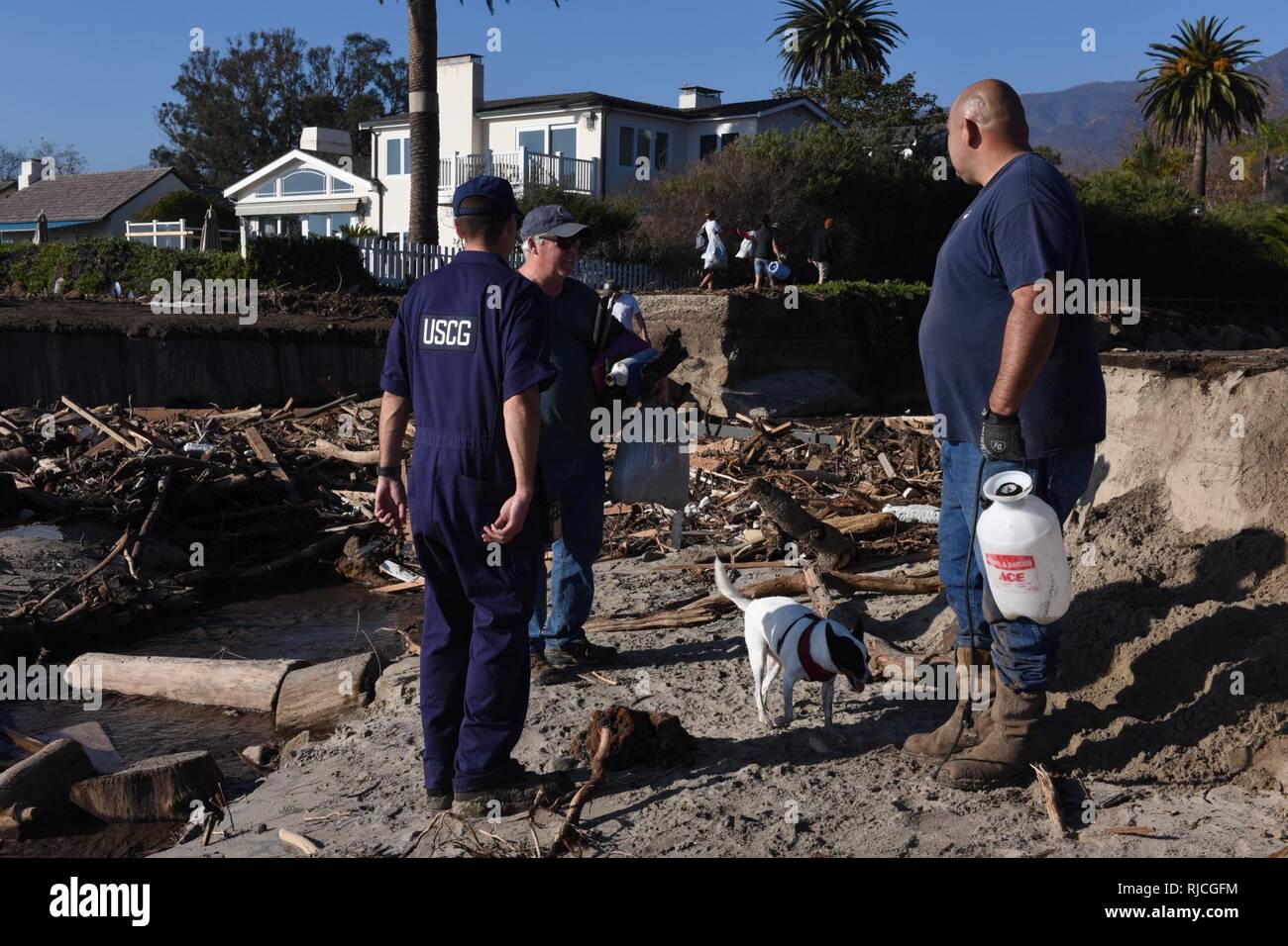 Petty Officer 2nd class Bret Weideman, Mitglied der Marine Sicherheit Loslösung Santa Barbara, zusammen mit den Auftragnehmern von Patriot Umwelt gemeinsam zu entwickeln, die beste Möglichkeit, um die Verunreinigung von einem Standort am Strand in Santa Barbara, Kalifornien, Jan. 11, 2018. Die Entfernung von gefährlichen Materialien wie Propan Behälter, Tanks, Fässer, Haushalt chemische Produkte sauber und auch Fahrzeuge, die entlang dem Strand hat die in den Mittelpunkt ihrer Bemühungen. Stockfoto