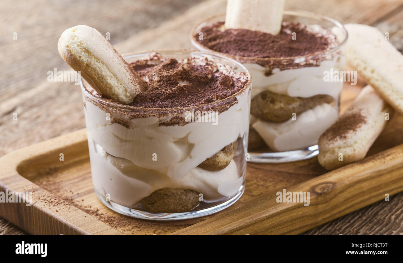 Traditionelle italienische Dessert Tiramisu in Gläsern auf rustikalen Holztisch, Nahaufnahme, selektiver Fokus Stockfoto