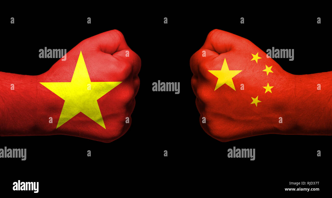 Flagge von Vietnam und China gemalt auf zwei geballte Fäuste nach einander auf schwarzem Hintergrund/Vietnam - China Beziehungen Konzept Stockfoto