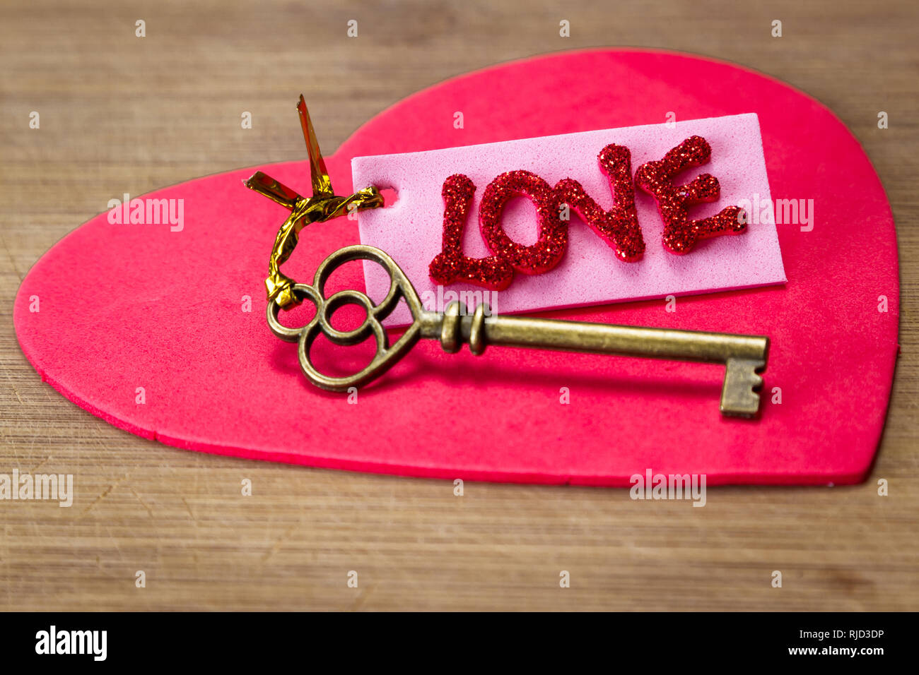 Konzeptionelle Bild mit einem alten Schlüssel mit einem rosa Tag mit rotem glitter Buchstaben Rechtschreibung das Wort Liebe Stockfoto