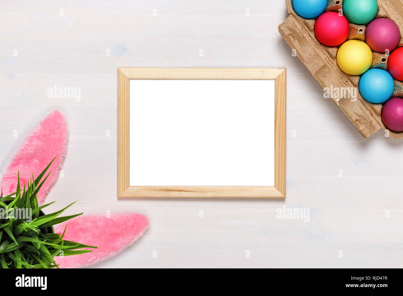 Ein Frame, bunny Ohren, einen Blumentopf mit künstlichem Gras, bunte Eier im Karton, Farben und Pinsel. Ostern Konzept. Platz kopieren Stockfoto