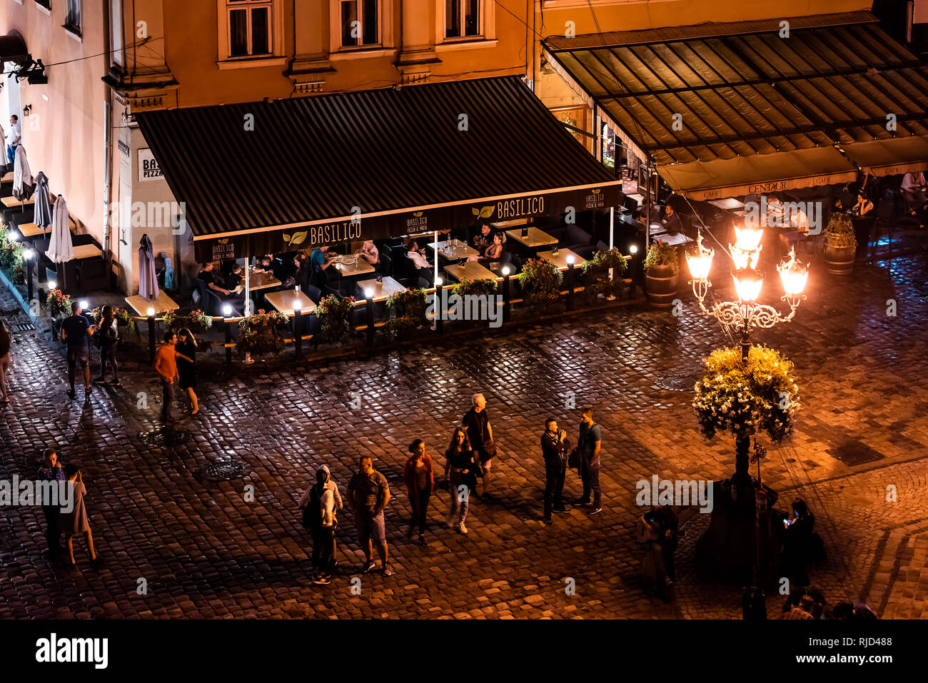 Lemberg, Ukraine - 31. Juli 2018: Antenne hohen Winkel Restaurant Basilico ukrainischen Stadt in der Altstadt Marktplatz mit nachts beleuchtete Menschen zu Fuß da Stockfoto