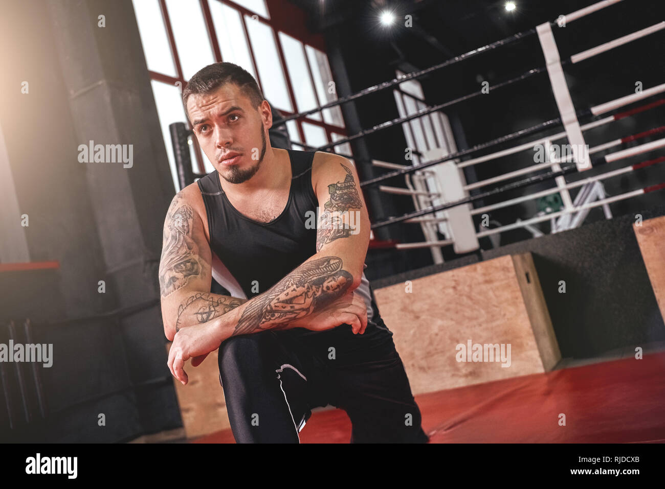 Schwerpunkt junge muskulöse Athleten in farbigen Sport Kleidung seine Muskeln Aufwärmen vor dem Training in schwarz Boxing Gym Stockfoto