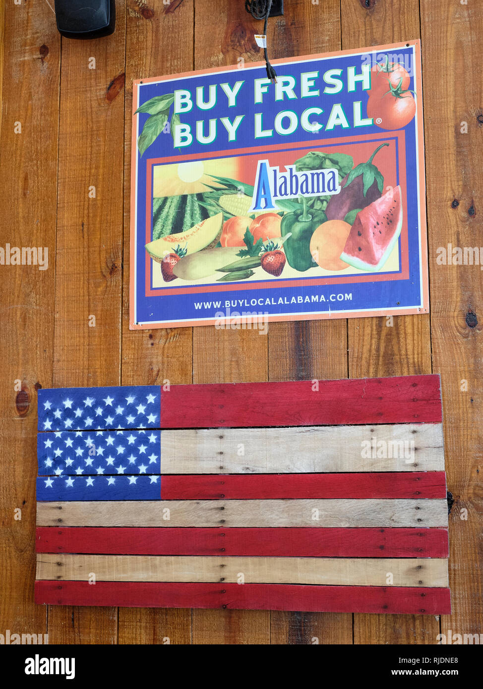 Frische lokale Zeichen Förderung Alabama Landwirtschaft über eine amerikanische Flagge auf Holz in einer ländlichen Alabama Bauernhof Markt in Hecht Straße Alabama gemalt, USA kaufen Kaufen Stockfoto