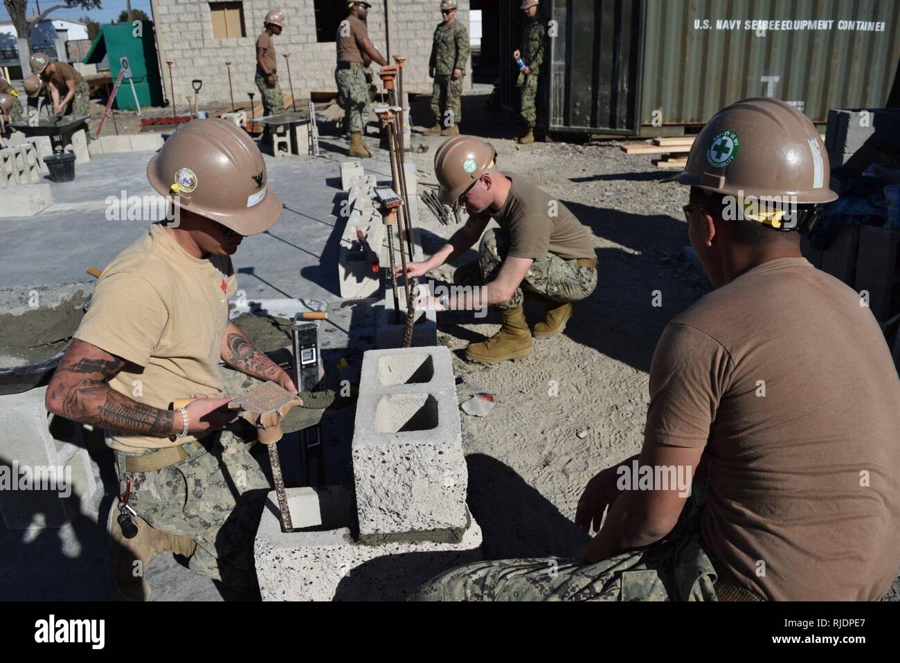 PORT HUENEME, Calif (Jan. 24,2018) Seabees, zugeordnet zu den Naval Mobile Konstruktion Bataillon Fünf (NMCB 5), zur Festlegung der Zement- und Bausteine der Grundstein für ein neues Gebäude in einem Baustein zur Ausbildung zu schaffen. NMCB 5 ist die Durchführung von Schulungen zu helfen, die Sicherheit, die richtige Technik Verwendung, gewährleisten und neue Seabees mit der Ausrüstung vertraut machen in der Vorbereitung für eine bevorstehende Bereitstellung. Stockfoto