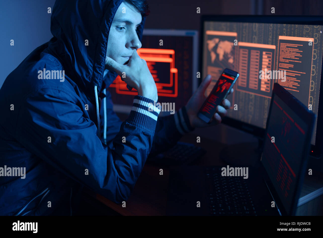 Hacker in einer Haube Nachdenken über das Problem des Hackens oder malware Infektion auf dem Hintergrund von Bildschirmen mit Codes im Neonlicht. Das Konzept der cybe Stockfoto