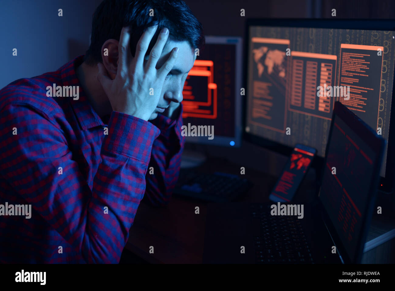 Männliche Hacker Gedanken über das Problem der Hacking oder malware Infektion auf dem Hintergrund von Bildschirmen mit Codes im Neonlicht. Das Konzept der cybersecu Stockfoto