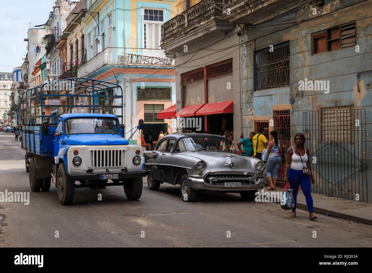 Szene auf eine typische Straße in Havanna in Kuba. Die Menschen vor Ort einkaufen und entlang wandern und einen alten amerikanischen Auto und einem sowjetischen Lkw fahren auf der Straße Stockfoto