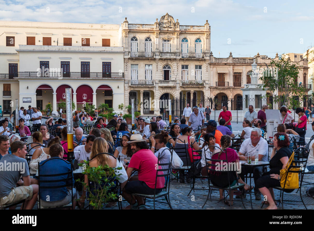 Menschen sitzen in einem Cafe in der Altstadt Platz Plaza Vieja mit Blick auf die spanischen Gebäuden im Kolonialstil in Havanna, Kuba Stockfoto