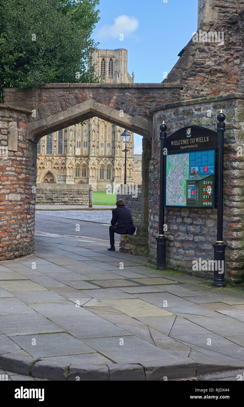 Ein Mann in der Nähe des Wells Cathedral sitzen. Wells, Somerset, Großbritannien Stockfoto