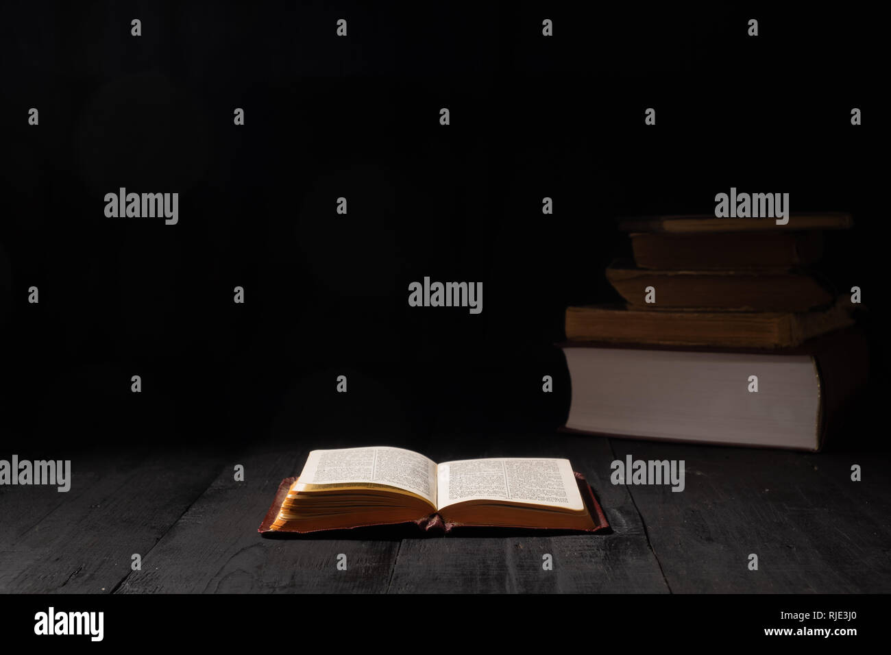 Buch der Bibel auf dunklen Tabelle öffnen. Low-key-Bild des Neuen Testaments in helles Licht bei Dunkelheit und Schatten Stockfoto