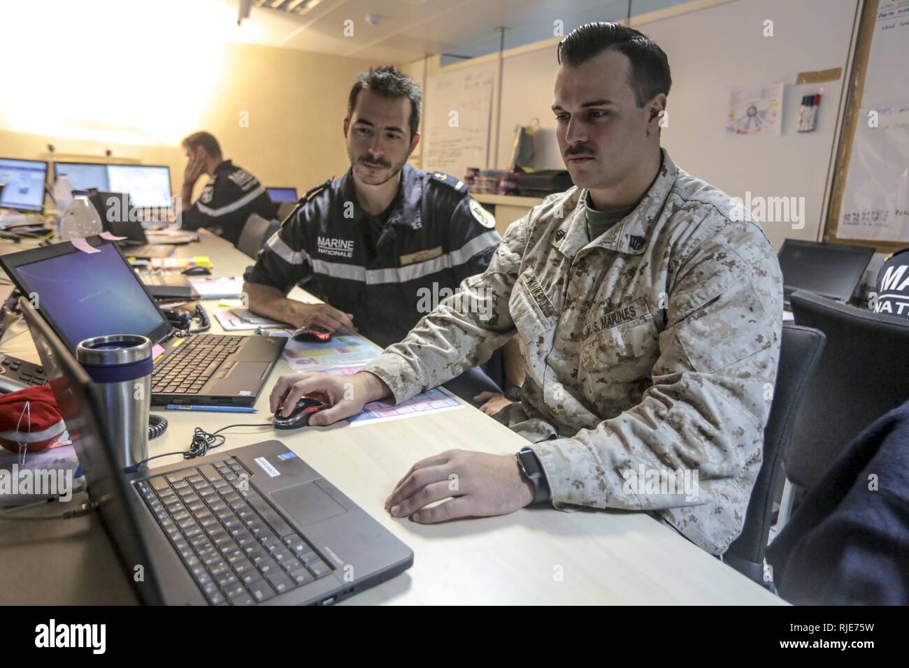 Sgt. Jeremy Kinkead, eine Mitteilung Spezialist mit Naval Amphibious Force, Task Force 51/5 th Marine Expeditionary brigade Behebt einen Computer mit einem französischen Amtskollegen an Bord der Französischen amphibisches Schiff Tonnerre während Bois Belleau 100 US/Französische Bereitstellung in der fünften Flotte Verantwortungsbereich. Stockfoto