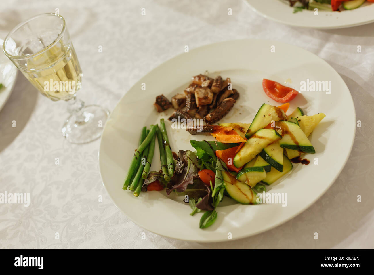 Gegrillter Oktopus auf weiße Platte serverd mit Weißwein, Ansicht von oben. Fisch und Meeresfrüchte. Stockfoto