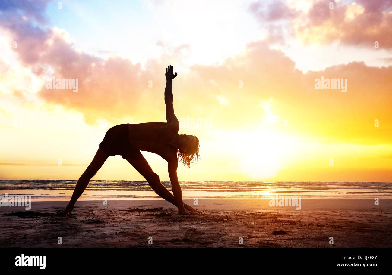 Passen Mann in silhouette Yoga am Strand in der Nähe des Ozeans an schönen Sonnenuntergang in Indien Stockfoto