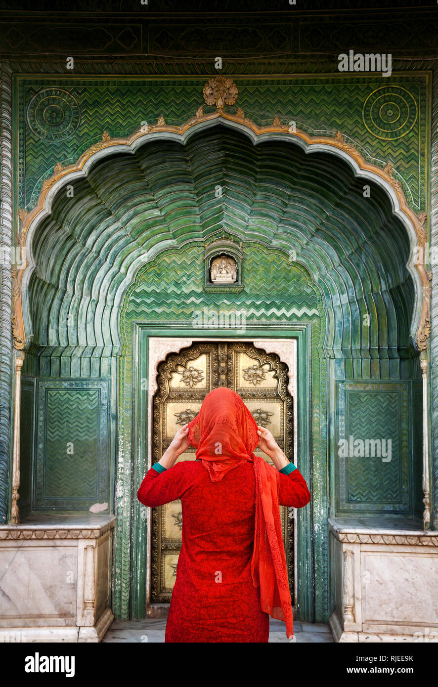 Indische Frau in rotem Schal suchen am grünen Tor im City Palace Jaipur, Rajasthan, Indien. Platz für Ihren Text, kann als Buch oder in einer Zeitschrift verwendet werden. Stockfoto